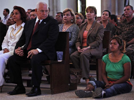 Una mujer desamparada se sienta junto a Micheletti, en una misa el lunes en Tegucigalpa. | AP