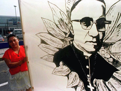 Una salvadorea junta a un retrato de Oscar Arnulfo Romero. |Reuters