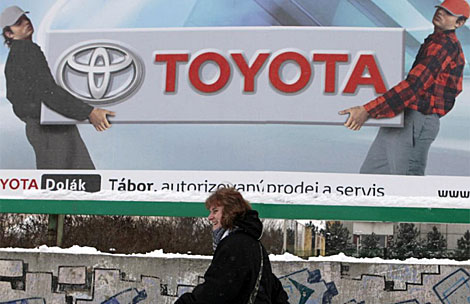 Una mujer pasea por una calle de Praga bajo un cartel de Toyota. | Reuters
