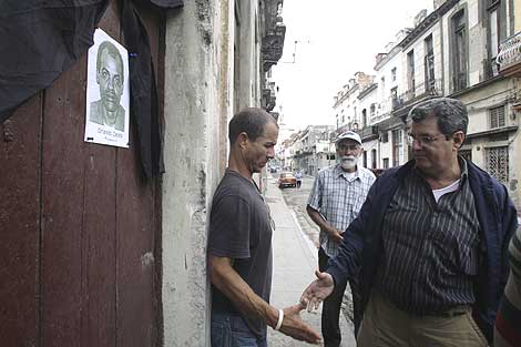 El activista cubano Oswaldo Pay (d) da el psame a un familiar de Orlando Zapata. | AP