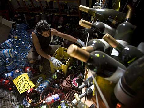 Un hombre organiza varias botellas tras el sesmo. | Efe