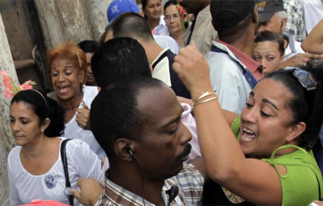 Miembros de seguridad forman una barrera entre manifestantes y las Damas de Blanco. | Reuters