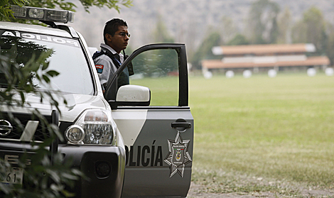 Un polica vigila las inmediaciones del Rancho de Cevallos, al fondo. | Efe