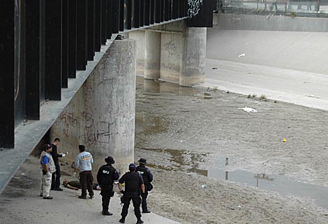 Agentes federales mexicanos observan el cadver del chico abatido en la frontera. | Ap