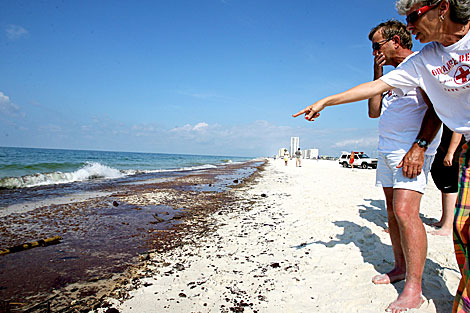 Dos personas observan una mancha de crudo en una playa de Gulf Shores, Alabama. | Efe