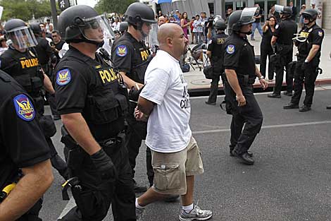 Agentes de la Polica de Phoenix trasladan esposado a un manifestante. | AP