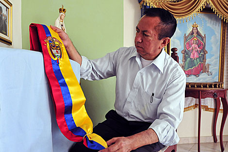 El sastre colombiano Luis Abel Delgado revisa la banda presidencial. | Efe