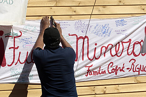 Un familiar de los mineros pone un cartel que dice 'Fuerza Mineros!'. | Reuters