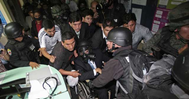 Correa, con máscara de gas y en silla de ruedas, abandona el hospital escoltado. | Ap