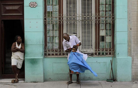 Un hombre corta el pelo a un niño en una calle de La Habana. I AP