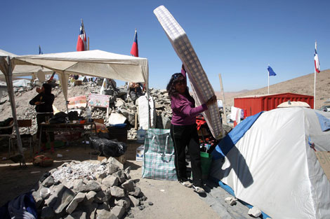 La familiar de un minero empaca sus cosas antes de abandonar el campamento. | AFP