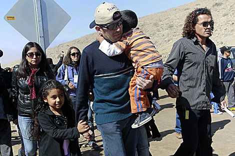 El minero Alex Vega (C) llega este domingo junta a su familia a la mina. | Reuters