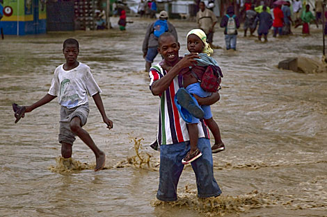 Un hombre carga a un nio en una calle inundada. | AFP