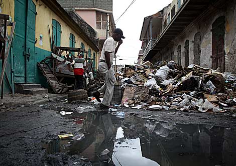 Un hombre cruza una calle de Cabo Haitiano convertida en basurero. | AFP