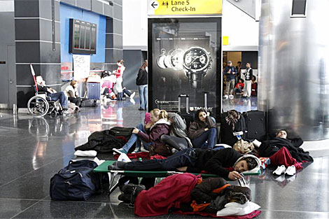 Varias personas descansan en el aeropuerto JFK de Nueva York a la espera de poder volar. | Reuters