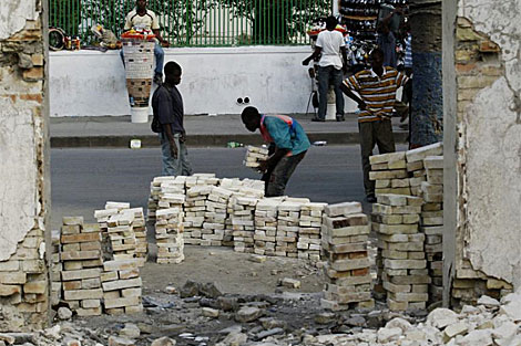 Un hombre roba este jueves ladrillos del Ministerio de Finanzas, dañado por el seísmo. | Reuters