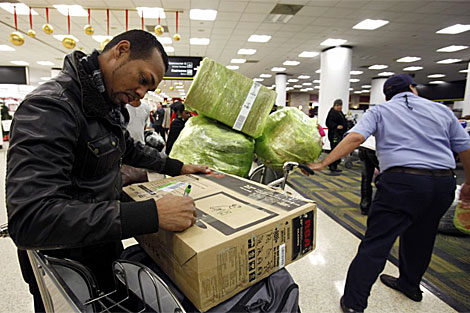Un pasajero cubano prepara un paquete en el aeropuerto de Miami antes de viajar a la isla. | AP