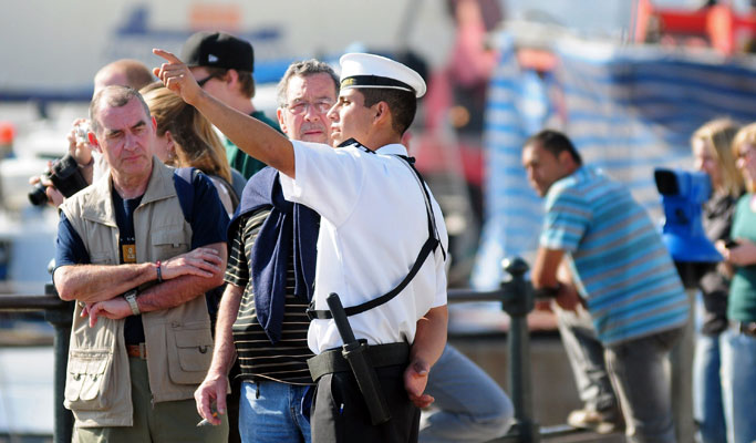 Un oficial habla con turistas en Valparaso tras la alerta de tsunami emitida por Piera. | AFP