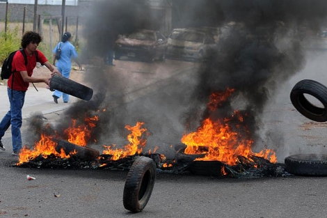Un joven arroja un neumático al fuego durante la protesta docente. | AFP