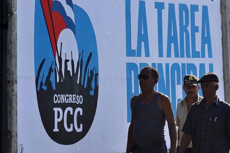 Cubanos frente a un cartel del VI Congreso del Partido Comunista. | Efe