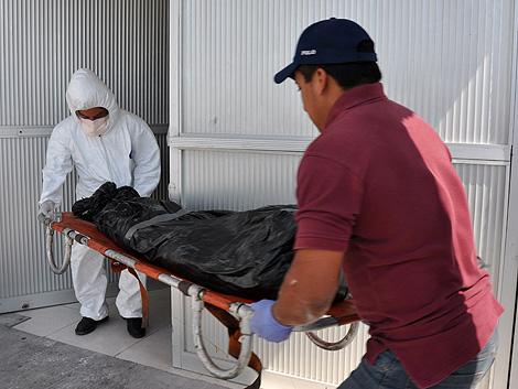 Personal forense transporta uno de los cuerpos hallados en Tamaulipas. | Afp