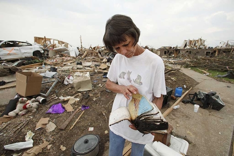 Una mujer mira una biblia mientras recupera algunos de sus bienes en Joplin. | AP