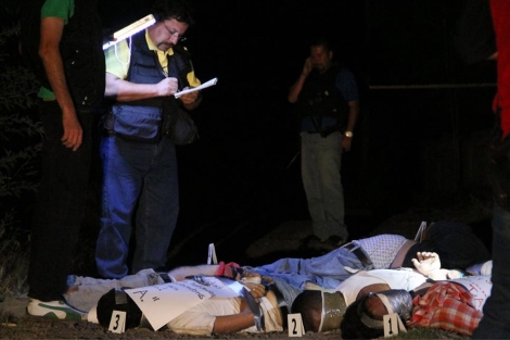 Un policía toma nota ante varios de los cadáveres.| Afp