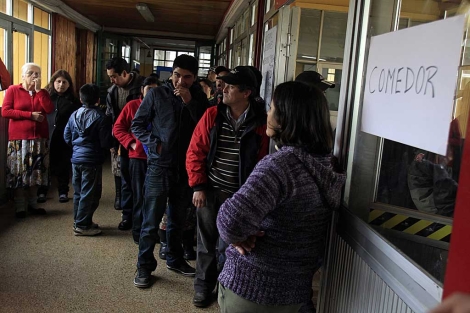 Pobladores de la comuna de Lago Ranco hacen fila para recibir alimentos. | Reuters