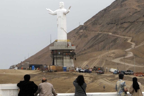 Varias personas observan la construcción del 'Cristo del Pacífico' en el Morro Solar de Lima. | Reuters