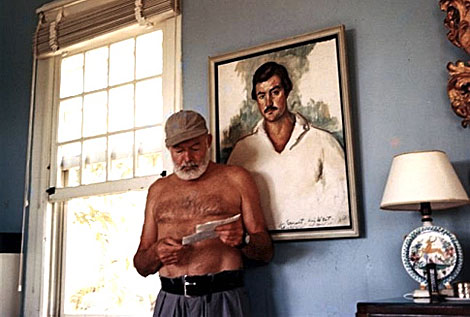 Hemingway en la Finca Viga, delante de un retrato suyo.