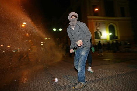 Un manifestante encapuchados tira piedras a los policas. | AFP
