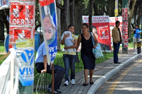 Dos mujeres pasean por una calle empapelada de propaganda electoral. I AFP
