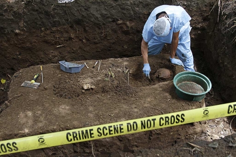 Un forense recupera restos humanos de una fosa ilegal en la que se hallaron 10 cadveres. | AP