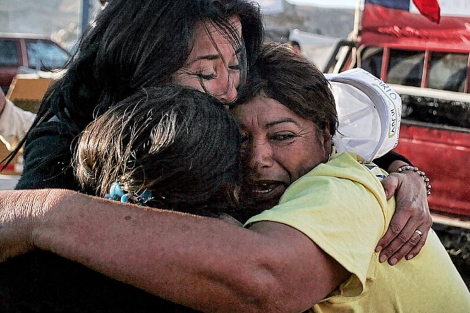 Tres mujeres se abrazan tras conocer que algunos de sus familiares estaban vivos.