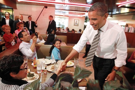 Obama saluda a una mujer y a su familia en un restaurante de Los ngeles. | Reuters