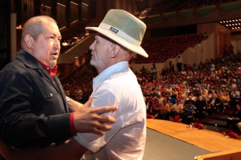 El presidente Hugo Chávez saluda a un hombre mayor frente al público. | Reuters