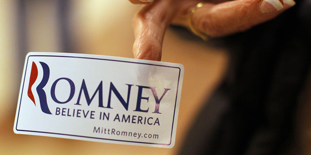 Un voluntario coloca una pegatina del aspirante republicano, Mitt Romney. | Reuters