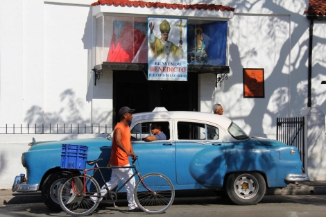 Un hombre camina por una calle de La Habana adornada con un cartel del Papa. | Efe