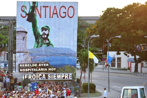 El Papa pasea en su vehculo por una calle de Santiago, con un cartel revolucionario al fondo. | Afp