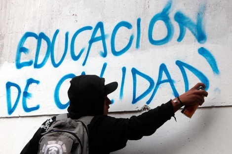 Un estudiante escribe un grafiti mientras participa en la manifestacin. | Efe