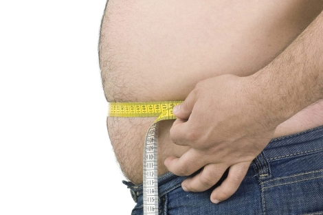 Un hombre obeso se mide la cintura. | El Mundo