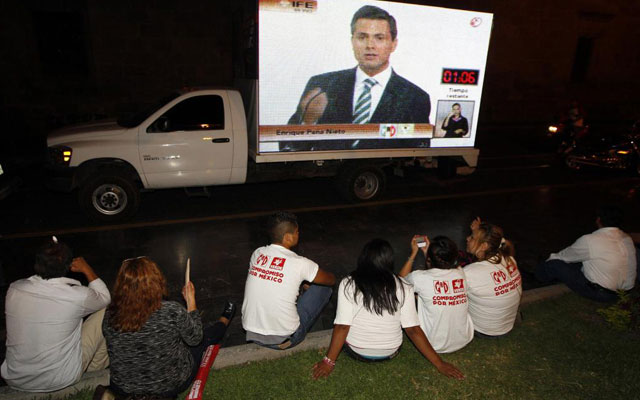 Varios ciudadanos ven en una pantalla gigante una intervencin de Pea Nieto.| Efe