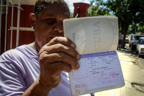 Una mujer muestra su pasaporte en regla y con permiso para viajar.| Afp