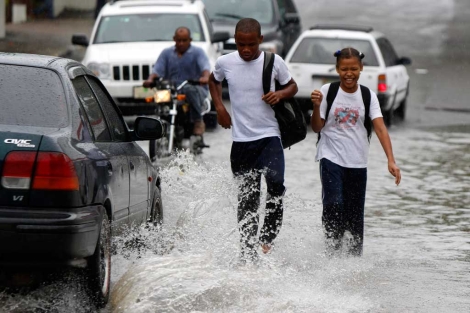 Dos escolares caminan por una calle inundada en Santo Domingo tras el paso del huracn. | Efe