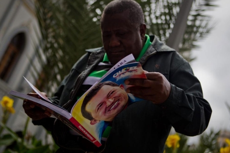 Un hombre sostiene un libro con la imagen del presidente Hugo Chávez.| Efe
