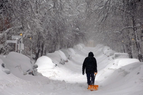 Un hombre camina con una pala con una calle de Boston. | Reuters