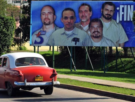 Un vehculo pasa en La Habana por un cartel alusivo a los cinco cubanos. | Efe