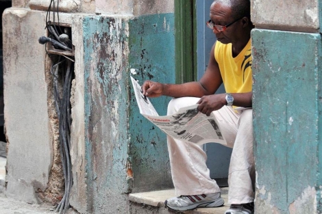Un hombre lee el peridico oficial en la puerta de su casa en La Habana. | E. M.
