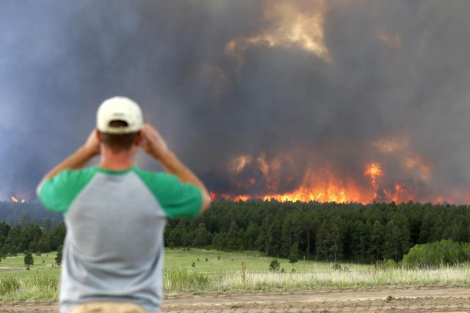 Un hombre observa las llamas del fuego forestal. | Reuters
