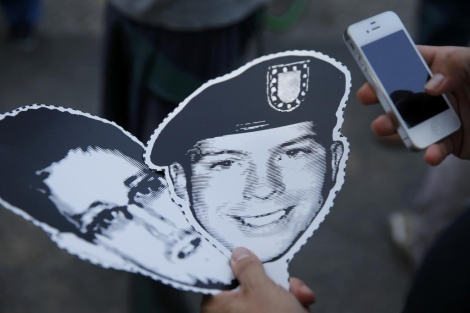 Una persona sostiene los retratos de Edward Snowden y Bradley Manning. | Reuters